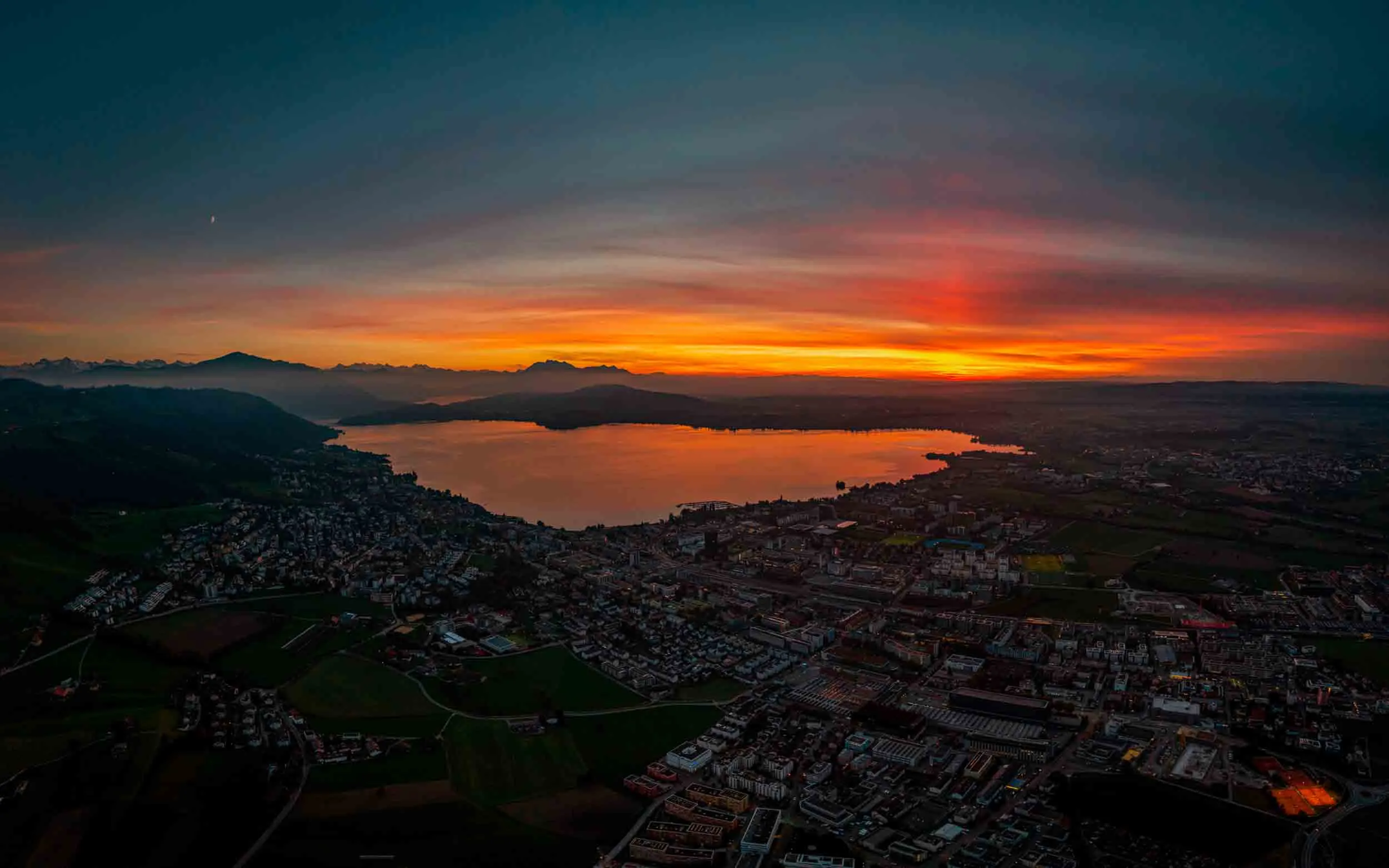 Aerial panorama of Zug city and Lake Zug during a fiery sunset, Switzerland